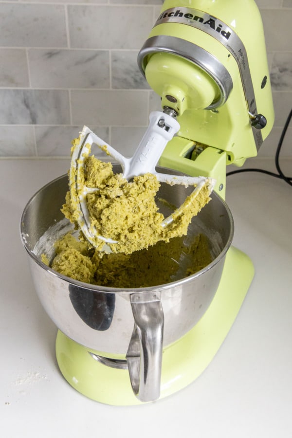 Final pistachio butter cookie dough on the beater of a stand mixer.