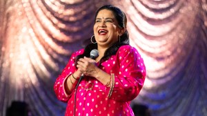 Zarna Garg wearing a bright pink kurta and laughing while holding a mic on stage in 'Practical People Win'