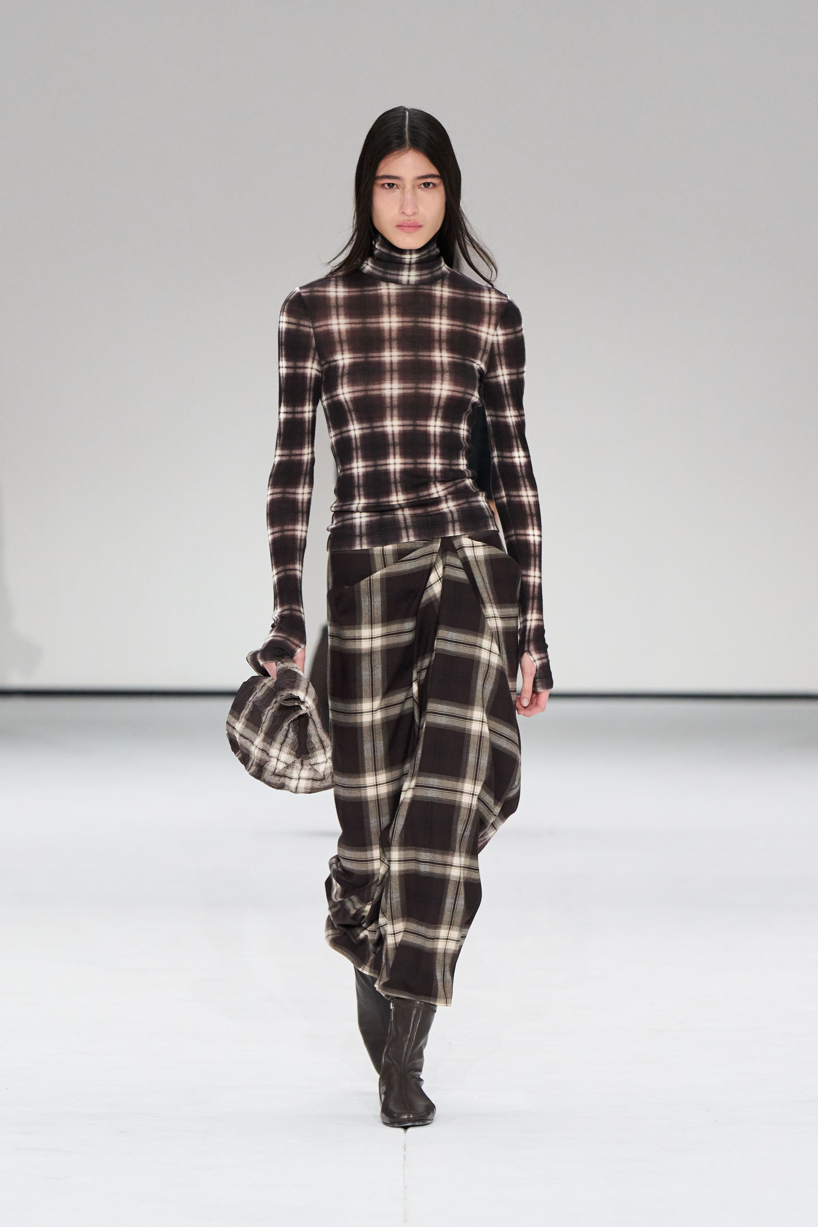 A woman wears a plaid shirt, plaid skirt at the cos show.