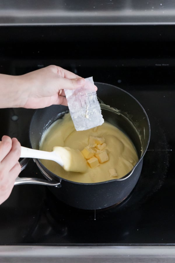 Adding cubes of butter to thickened custard.
