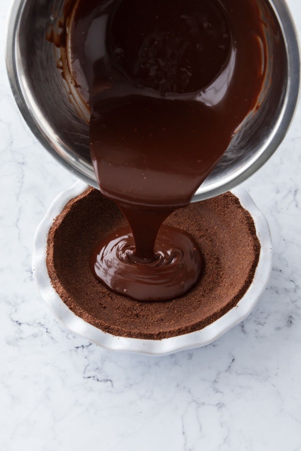 Pouring chocolate ganache into the pre-baked graham cracker pie crust.