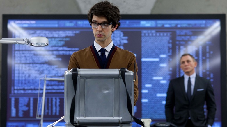 Q, sytanding in front of James Bond in No Time to Die