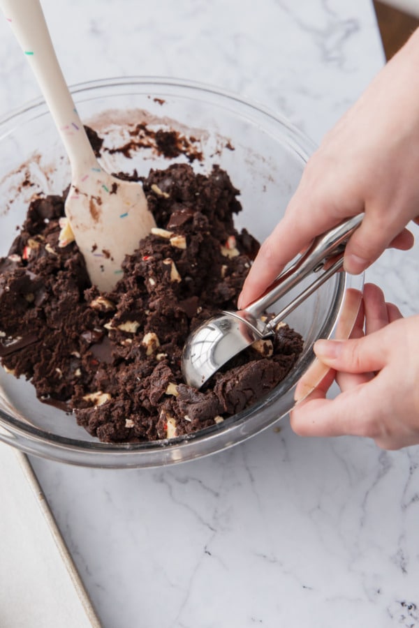 Scooping chocolate peppermint cookie dough with a large cookie scoop.